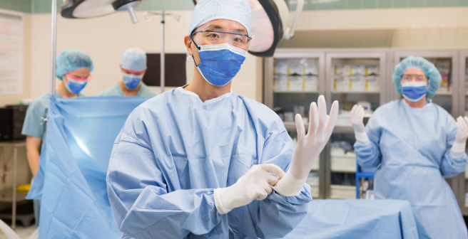 man wearing proper hand, eye, and body protection for a surgical room environment